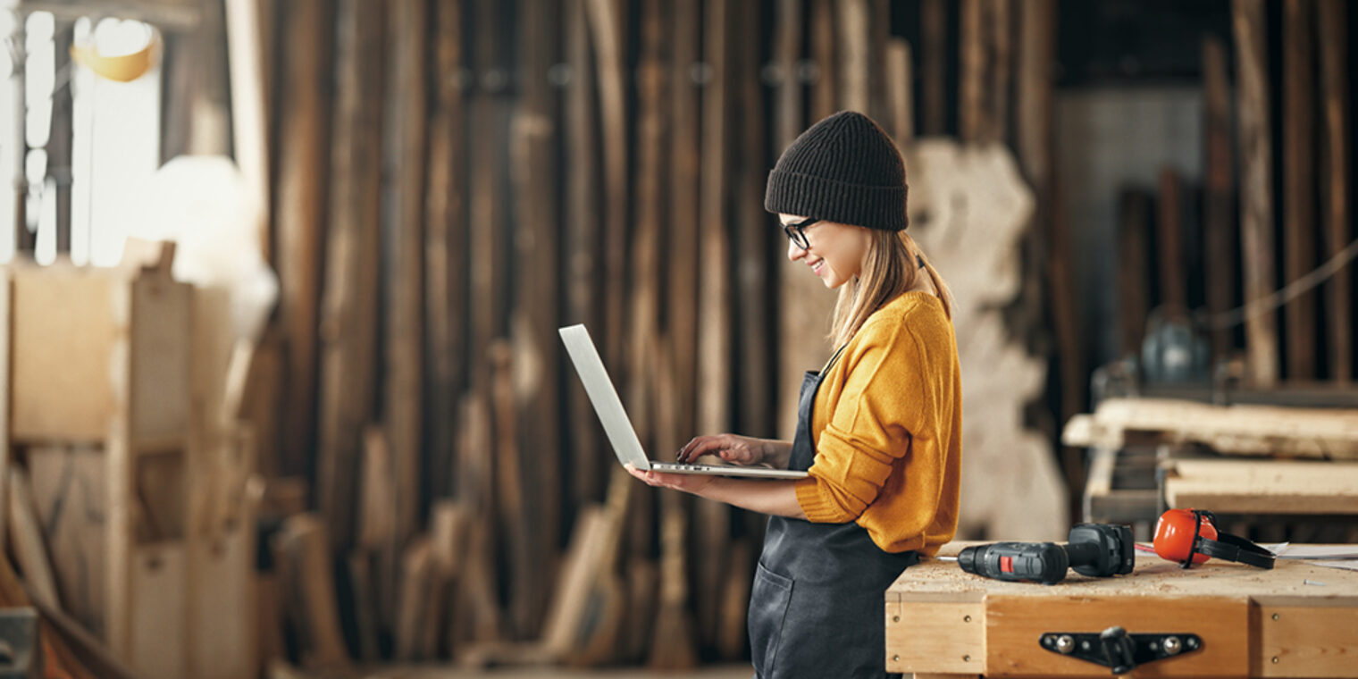 young female carpenter looks drawings on a laptop during while break in working with wood in modern handicraft studio Schlagwort(e): female, wood, work, tool, carpenter, workshop, woman, craftsman, handicraft studio, carpentry, craft, worker, joiner, occupation, professional, hand, caucasian, woodwork, person, industry, people, woodworker, equipment, construction, artisan, manual, diy, timber, wooden, plank, furniture, profession, manufacturing, business, workbench, beard, young, instrument, lumber, trade, laptop, break, board, computer, hat, handmade, happy, protective, job, master